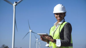 Woman with hard hat against wind turbine