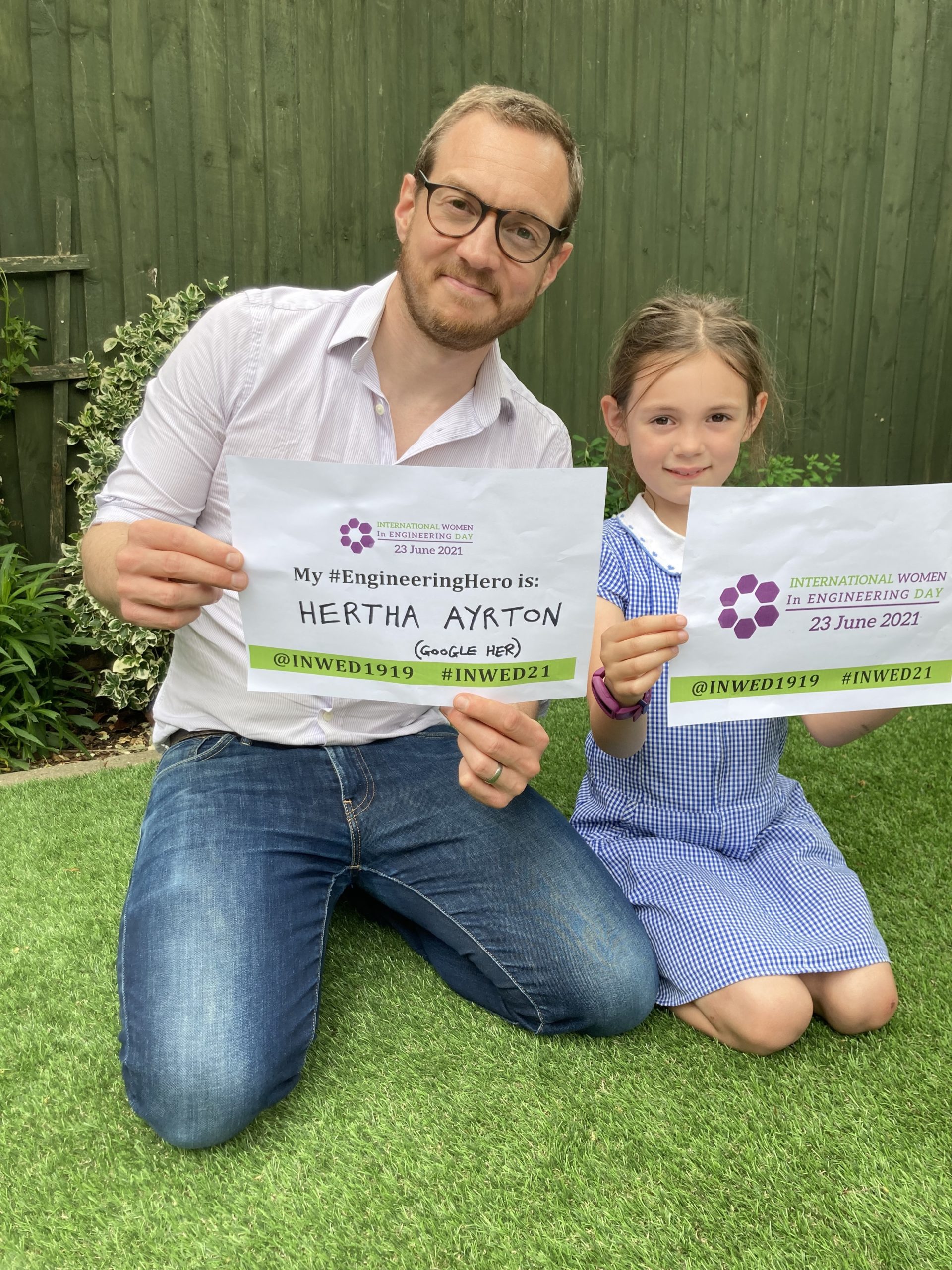 Photo of Mat Parker and his daughter holding signs to celebrate International Women In Engineering Day