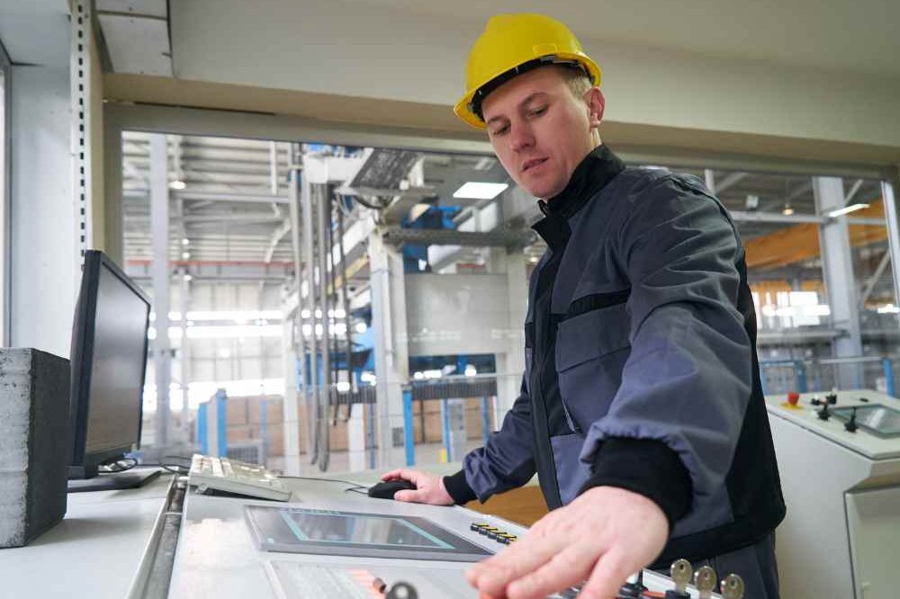 Man In Yellow Hard Hat Working At Controls Aspect Ratio 1200 800