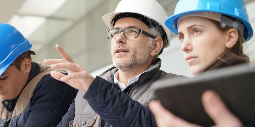 A Group Of People In Hard Hats Looking At Blueprints Aspect Ratio 1160 580