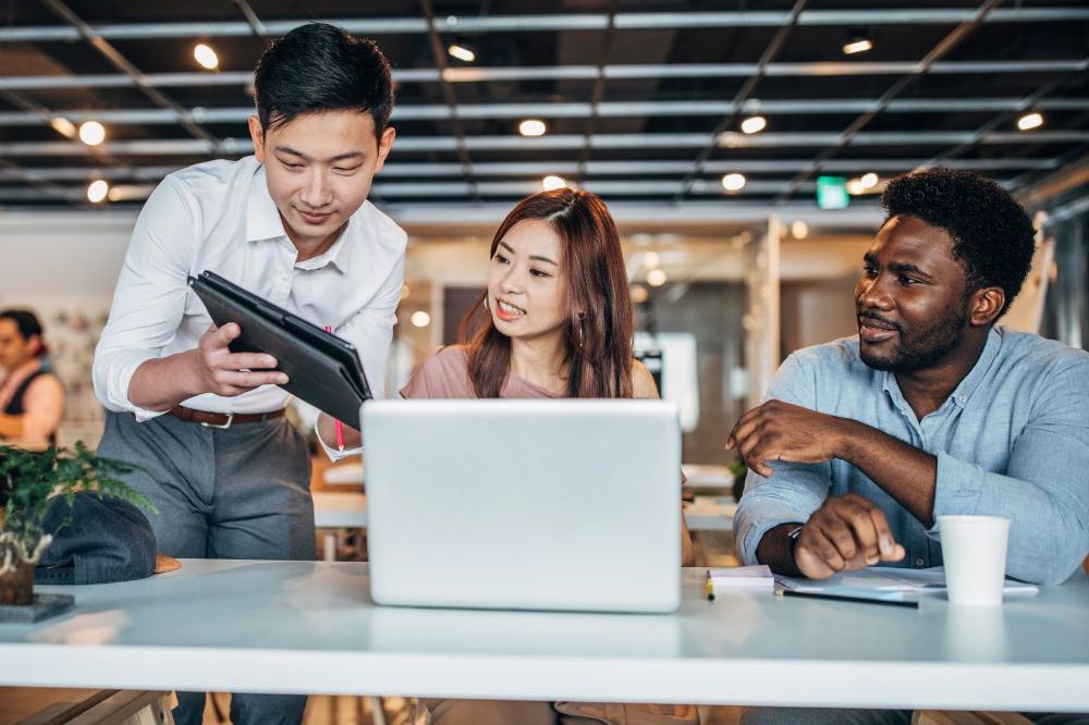 Three People Working On A Laptop In An Office