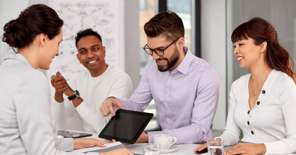 A Group Of People Sitting At A Table In An Office Aspect Ratio 760 400