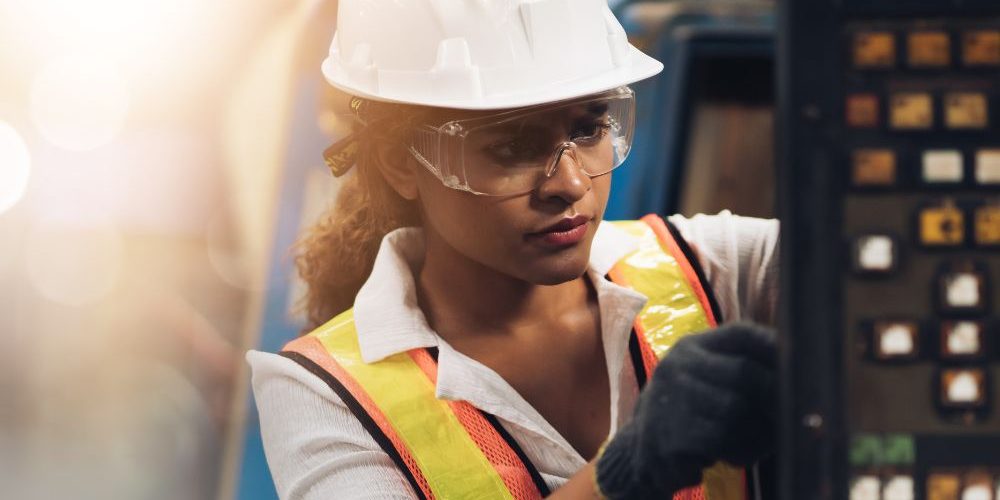 A Woman In A Hard Hat And Safety Glasses Working On A Machine Aspect Ratio 1160 580