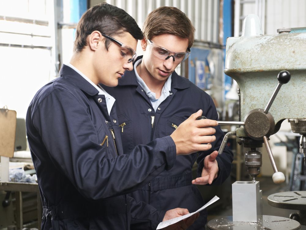 Two Men Working On A Machine In A Factory