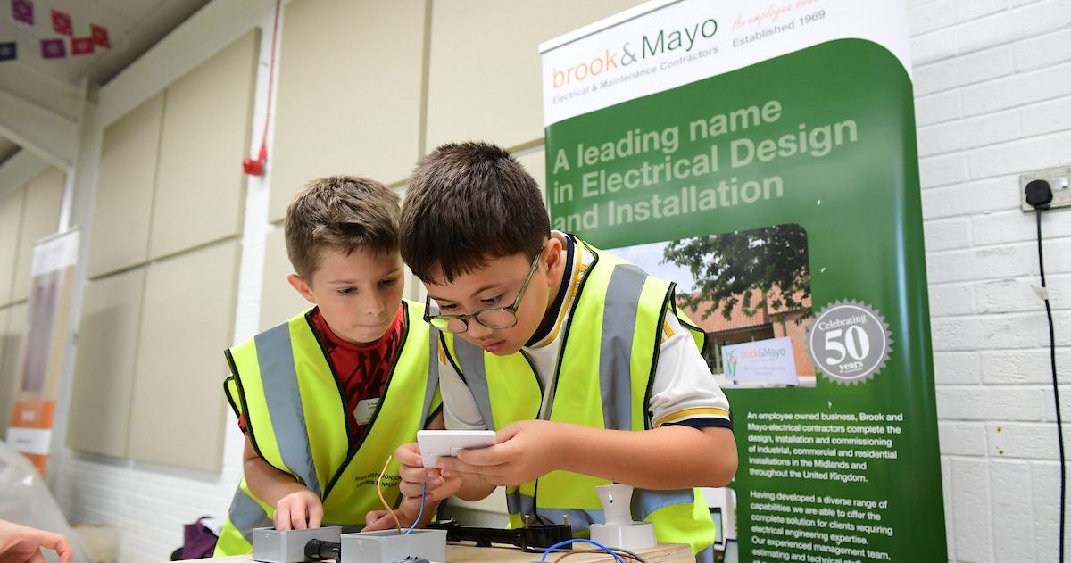C&EW 2024  Two Young Boys Wearing High Visibility Vests Work Together On An Electrical Project At A Workshop Table.