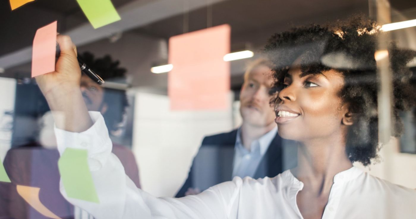 Project Management training - Woman Writing On Post It Note In Office