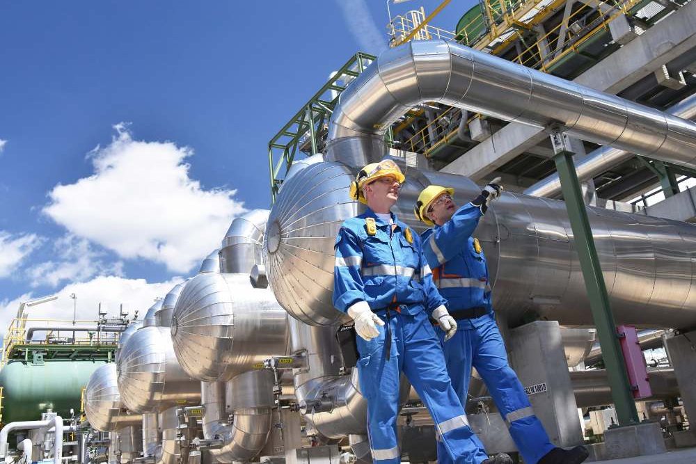 Two People On Site Talking Wearing Blue Overalls