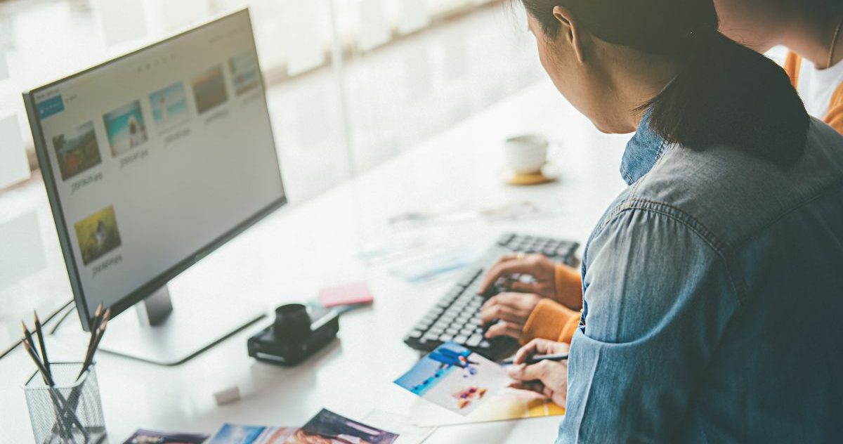 Two People Working On A Computer At A Desk