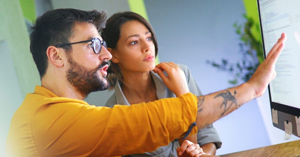 Two People Working On A Computer In An Office
